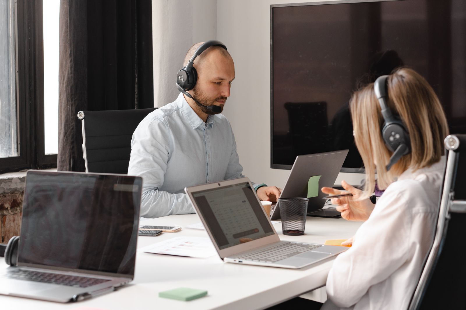 Customer support specialists working together with headsets and laptops