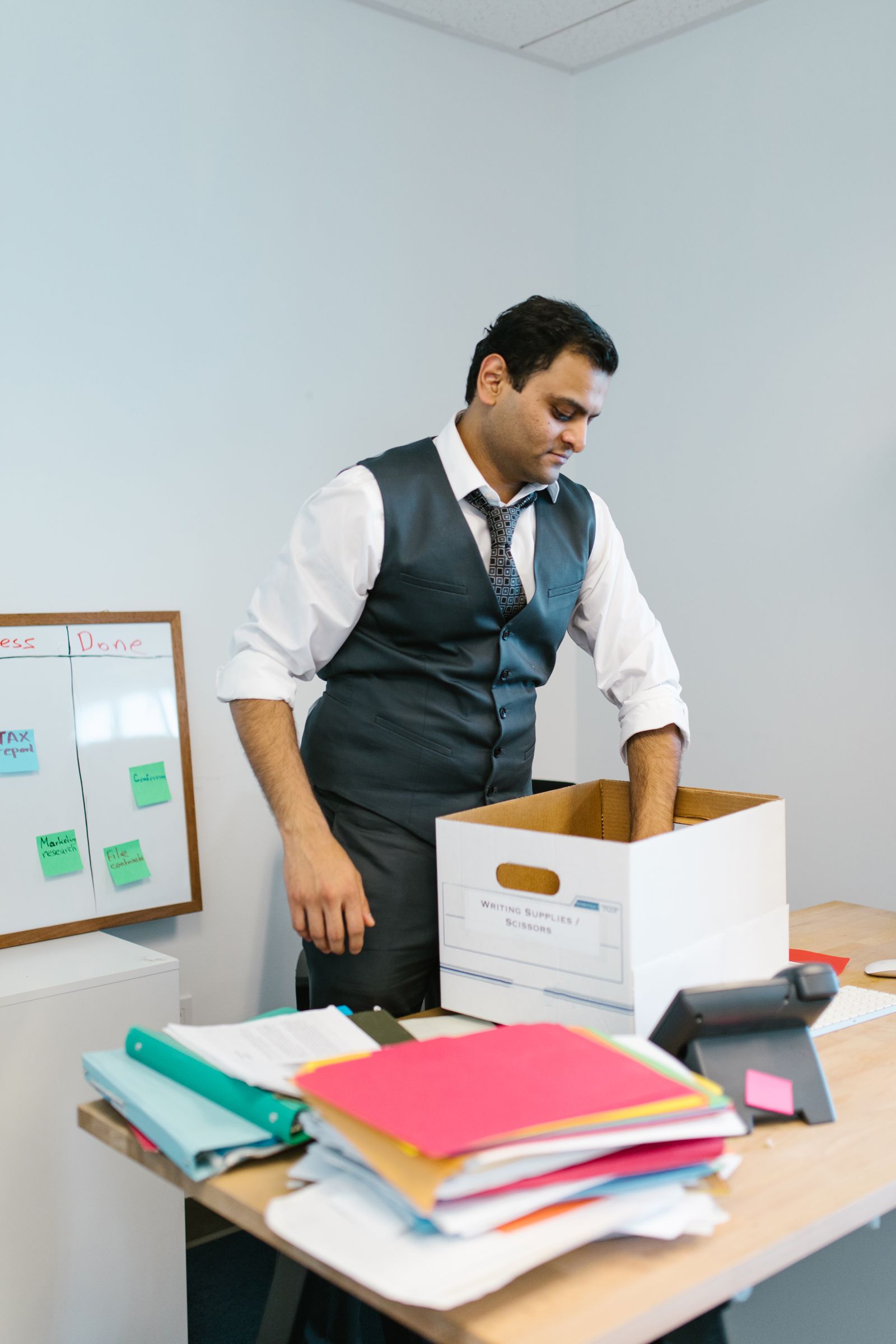 Professional employee packing belongings at an office desk during a workplace transition