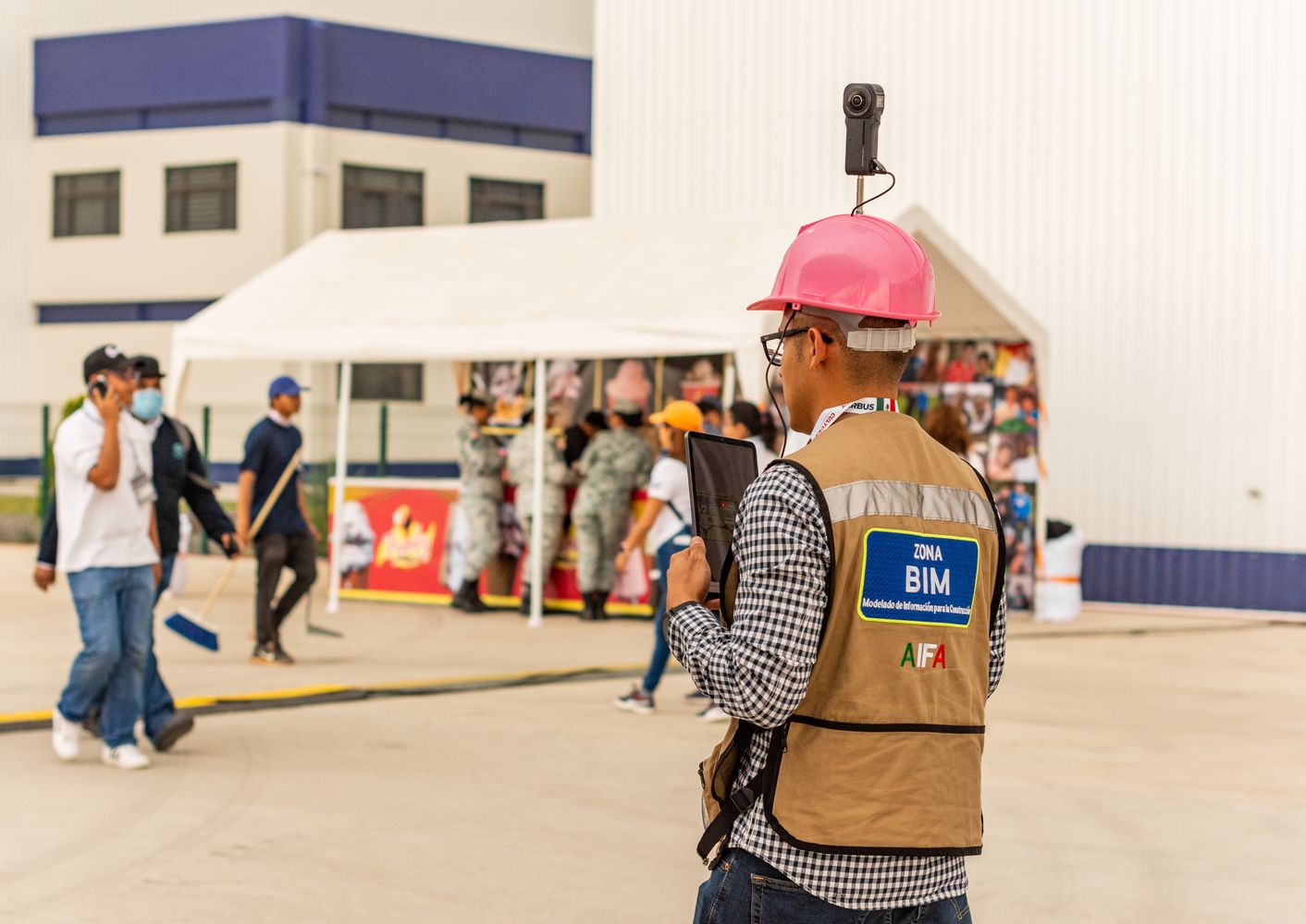 Construction professional using a tablet and helmet-mounted camera to document site conditions