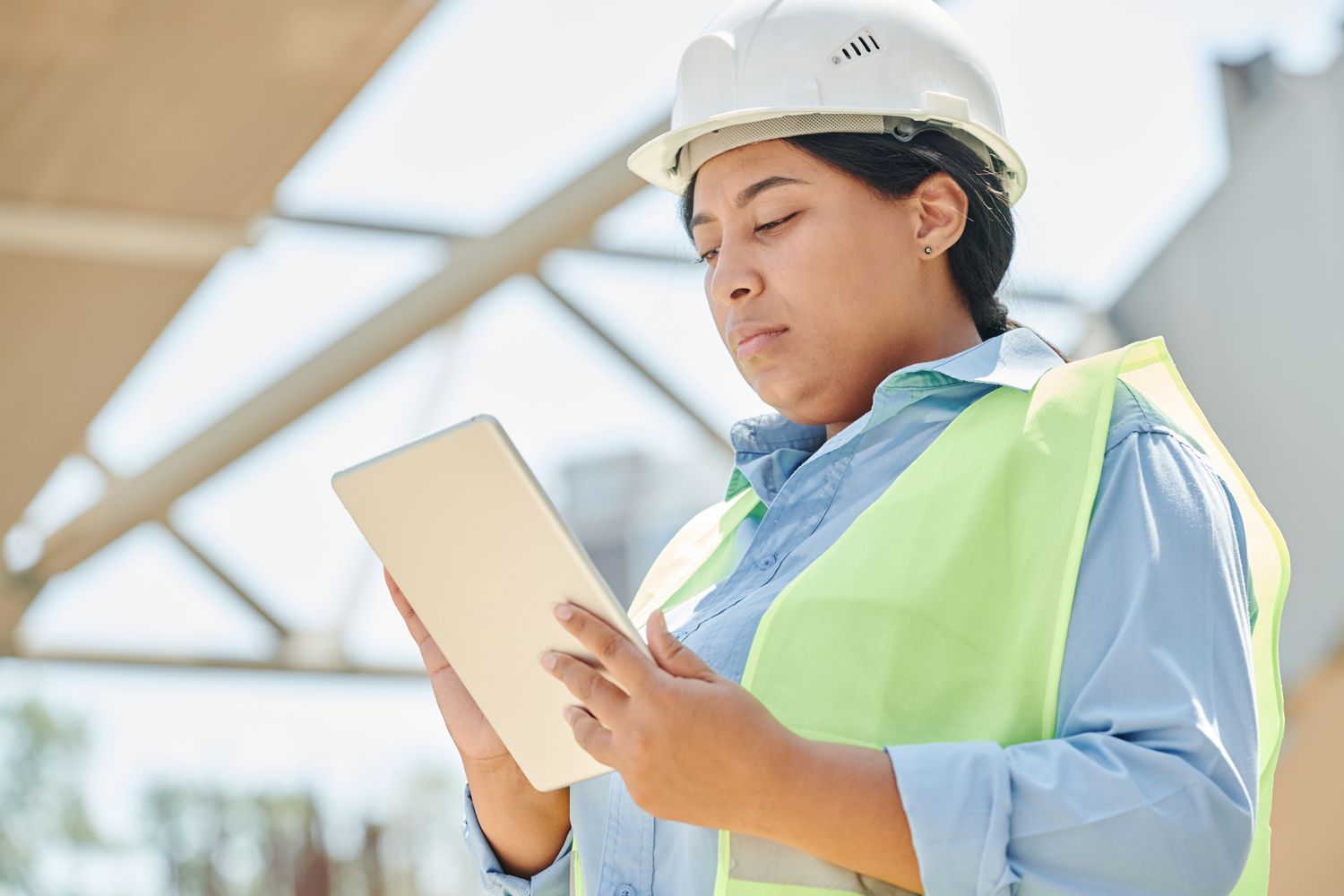 Field engineer in a hard hat and high-visibility vest using a tablet
