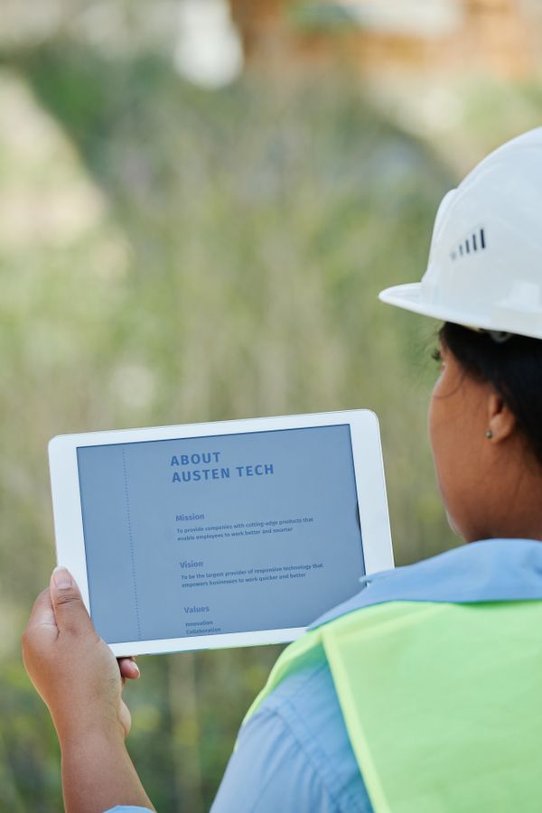 Construction professional in safety gear reviewing site plans on a tablet